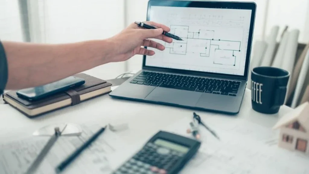 Drafter updating permit drawings on a laptop after review comments