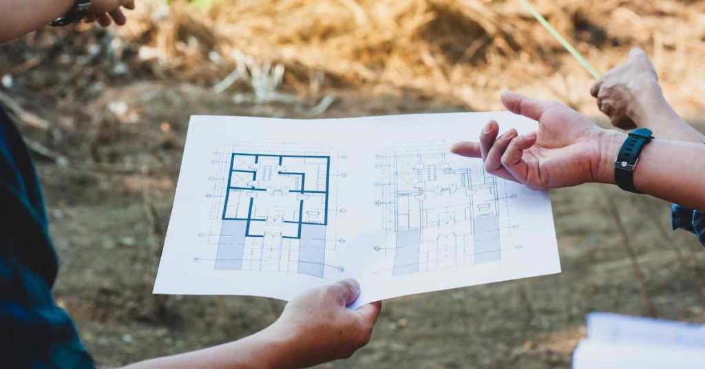 Hands holding a marked-up permit drawing during correction review